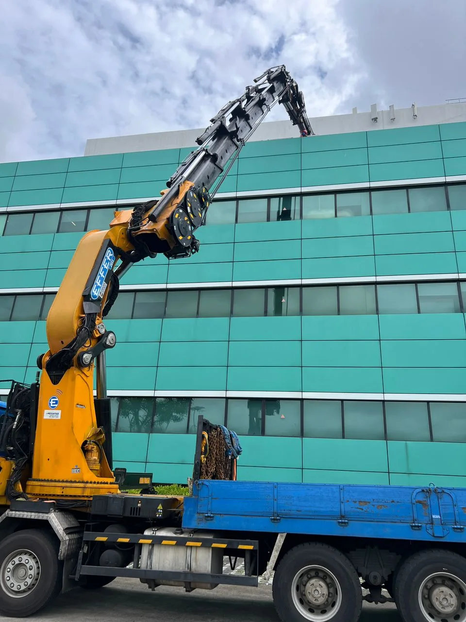 Long-reach crane operating beside industrial building